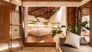 A modern bedroom with a sloped ceiling, a large bed, a sofa, and a dining area. - Stunning 2-BR Penthouse with view 800m to beach (Kecamatan Mengwi)