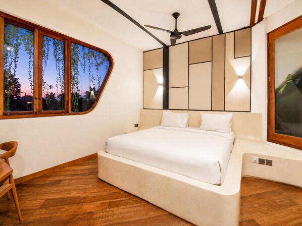 Een slaapkamer met een bed, een plafondventilator, een raam met uitzicht en een houten vloer.