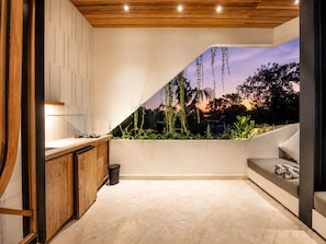 Een moderne keuken met een inbouwspoelbak, houten kastjes en uitzicht op een ondergaande zon door een raam.
