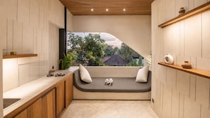 Una cocina moderna con un banco integrado, estanterías de madera y vistas al exterior con vegetación.