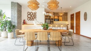 Una cocina moderna con una isla central, sillas de madera y lámparas de mimbre colgantes.