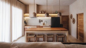 A modern kitchen with a central island, bar stools, hanging pendant lights, and wooden cabinetry. - Serene 3BR Villa, Stylish Interiors, beach close (Uluwatu)