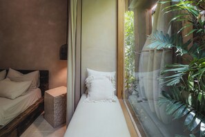 A bedroom with a bed, a small bedside table, and a window with a view of greenery. - Serene 3BR Villa, Stylish Interiors, beach close (Uluwatu)