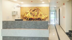 Un espace d’accueil doté d’un comptoir en marbre, d’un ventilateur fixé au mur et d’une sculpture décorative en relief doré.