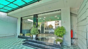 L’entrée d’un hôtel, avec une porte en verre, des marches menant à cette porte et des plantes en pot.