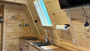 A kitchen with wooden cabinetry, a sink, a window, and a ceiling fan. - Sister A-Frame in Woods B (Oakland)