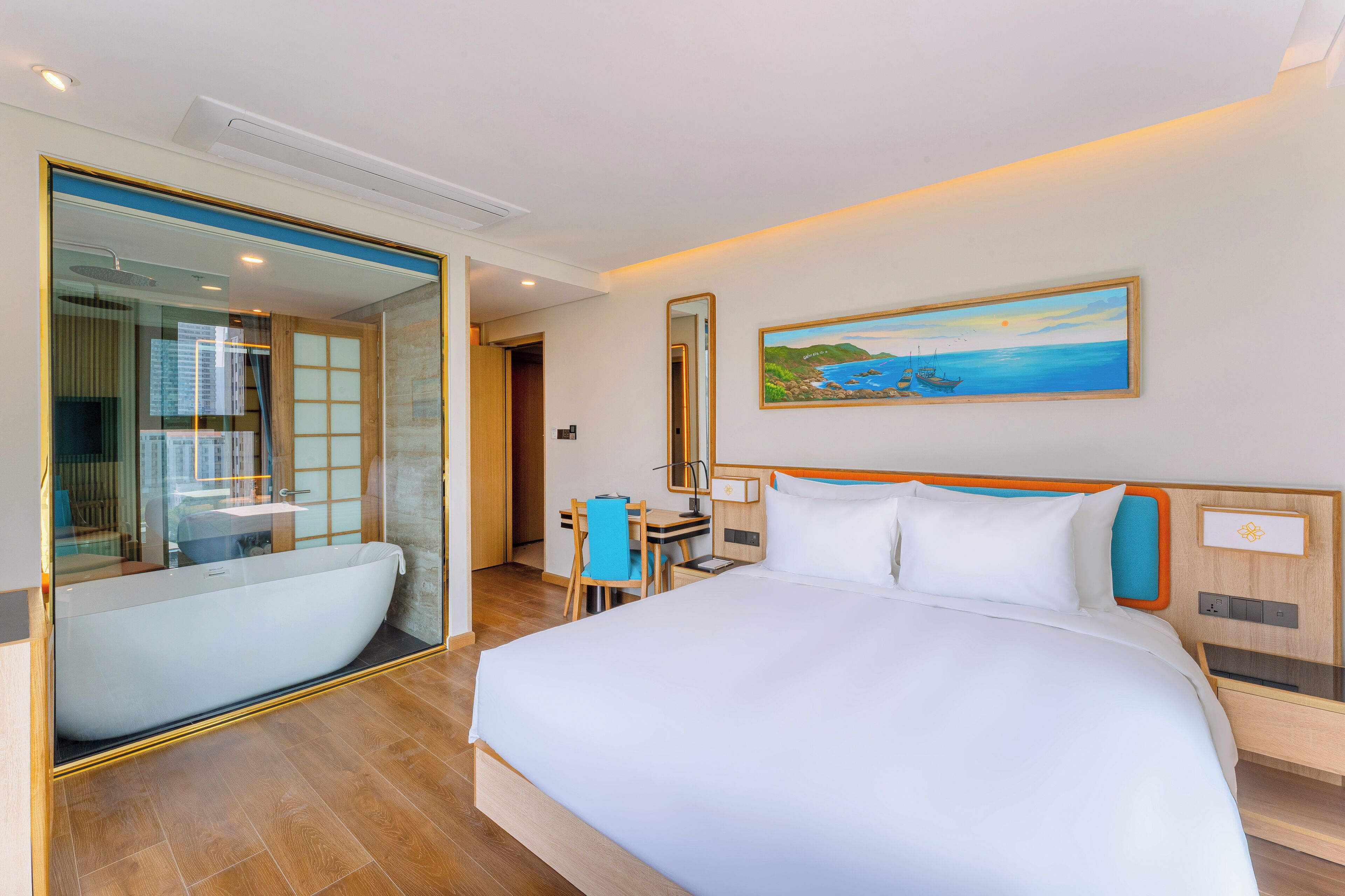 A hotel room with a large bed, a desk with a chair, a bathtub, and a painting on the wall.