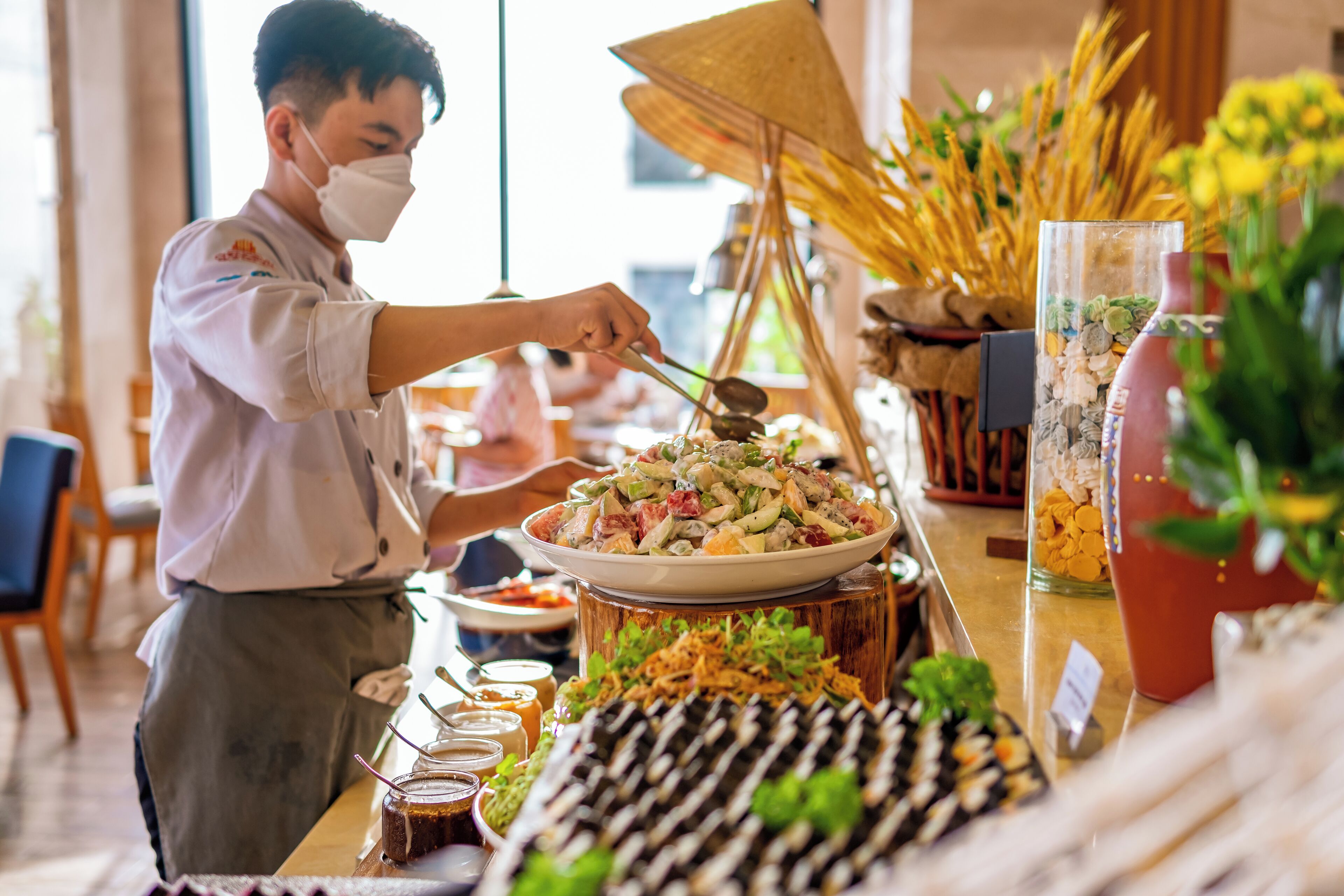 A buffet setup with various dishes and a person serving food.