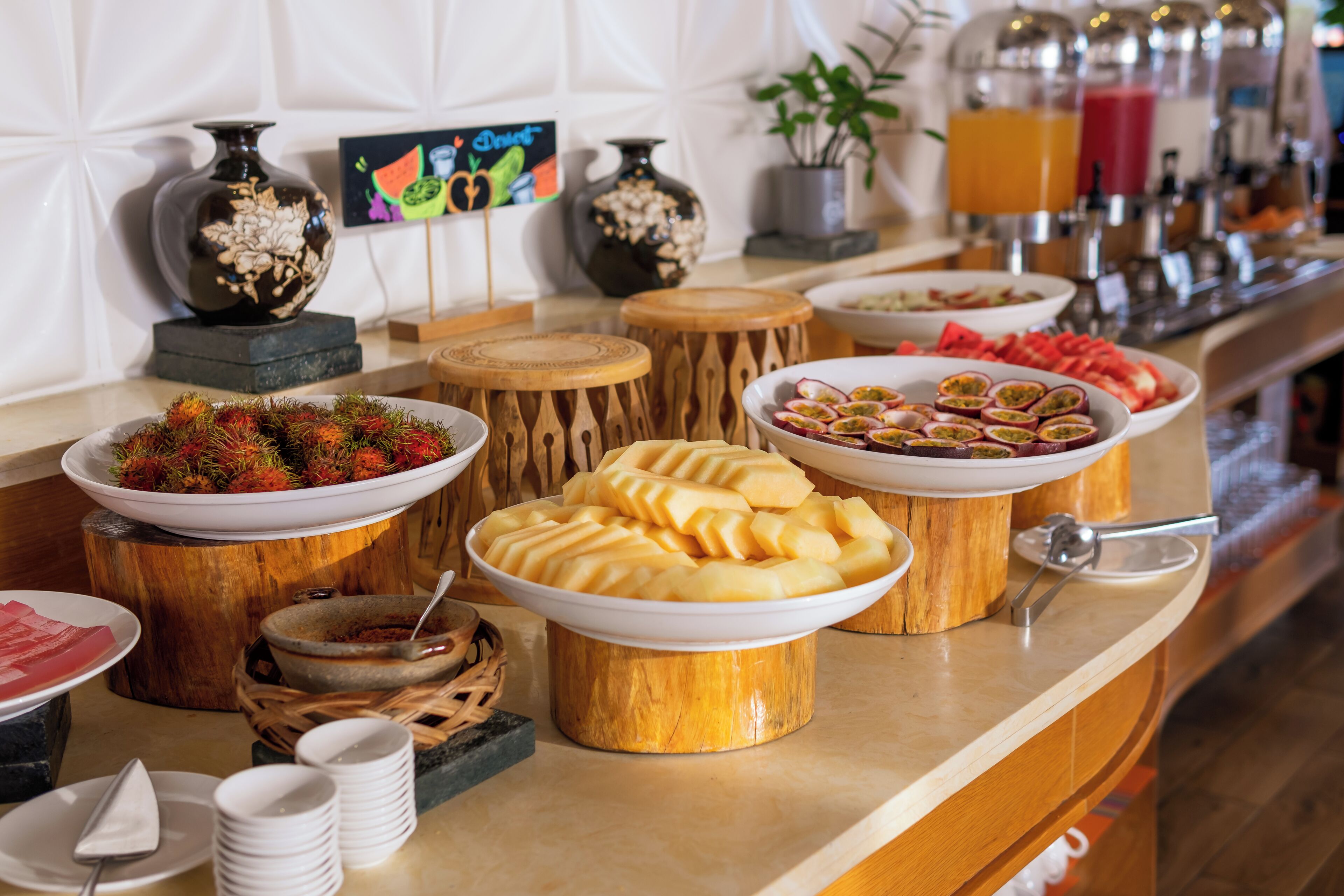 A buffet with various dishes, including fruits and pastries, arranged on a wooden stand.