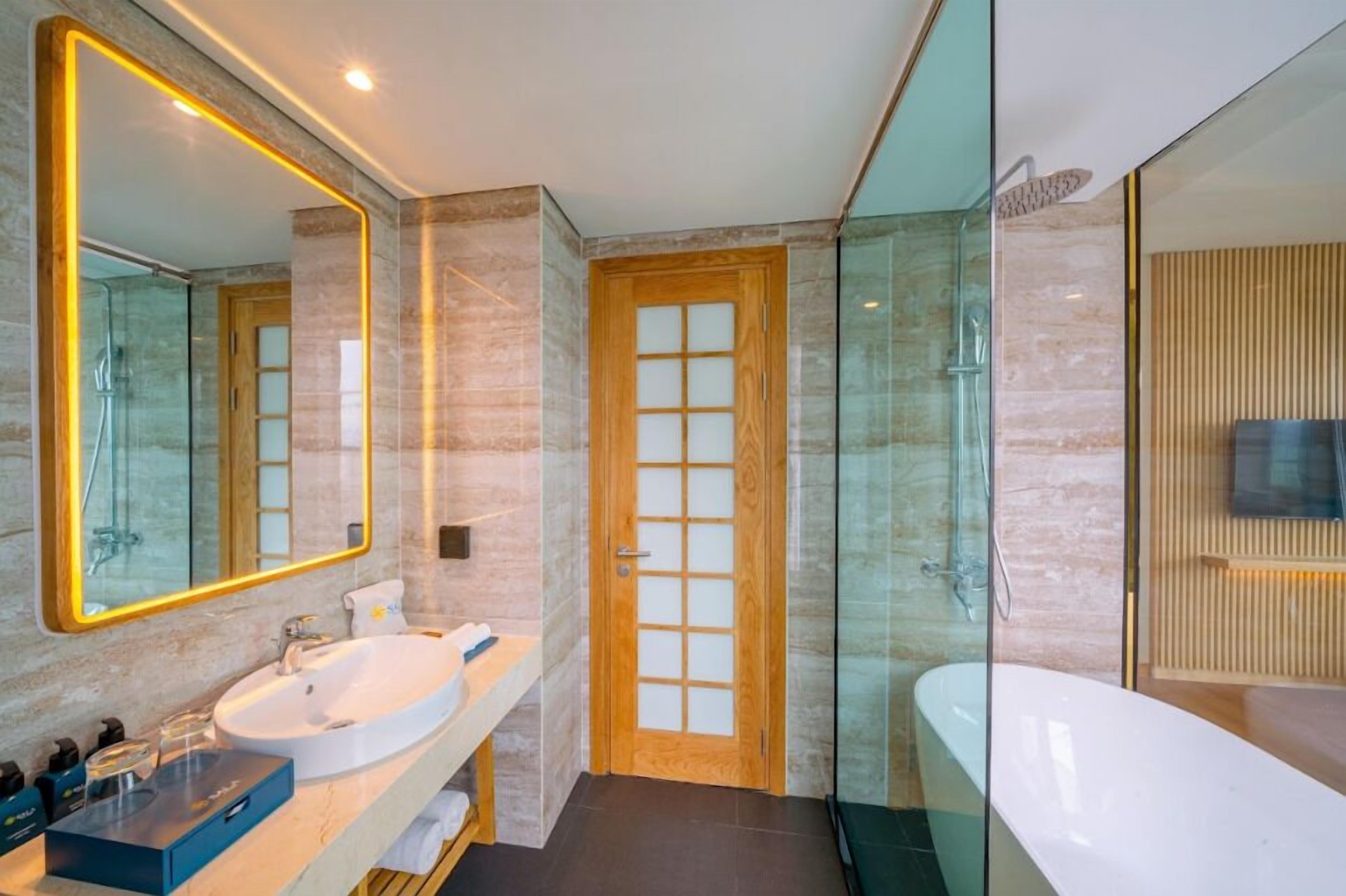 A modern bathroom with a large mirror, a round sink, a glass shower enclosure, and a separate bathtub.