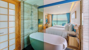 Een moderne hotelkamer met een ruime badkuip, een aparte douche en een balkon met uitzicht.