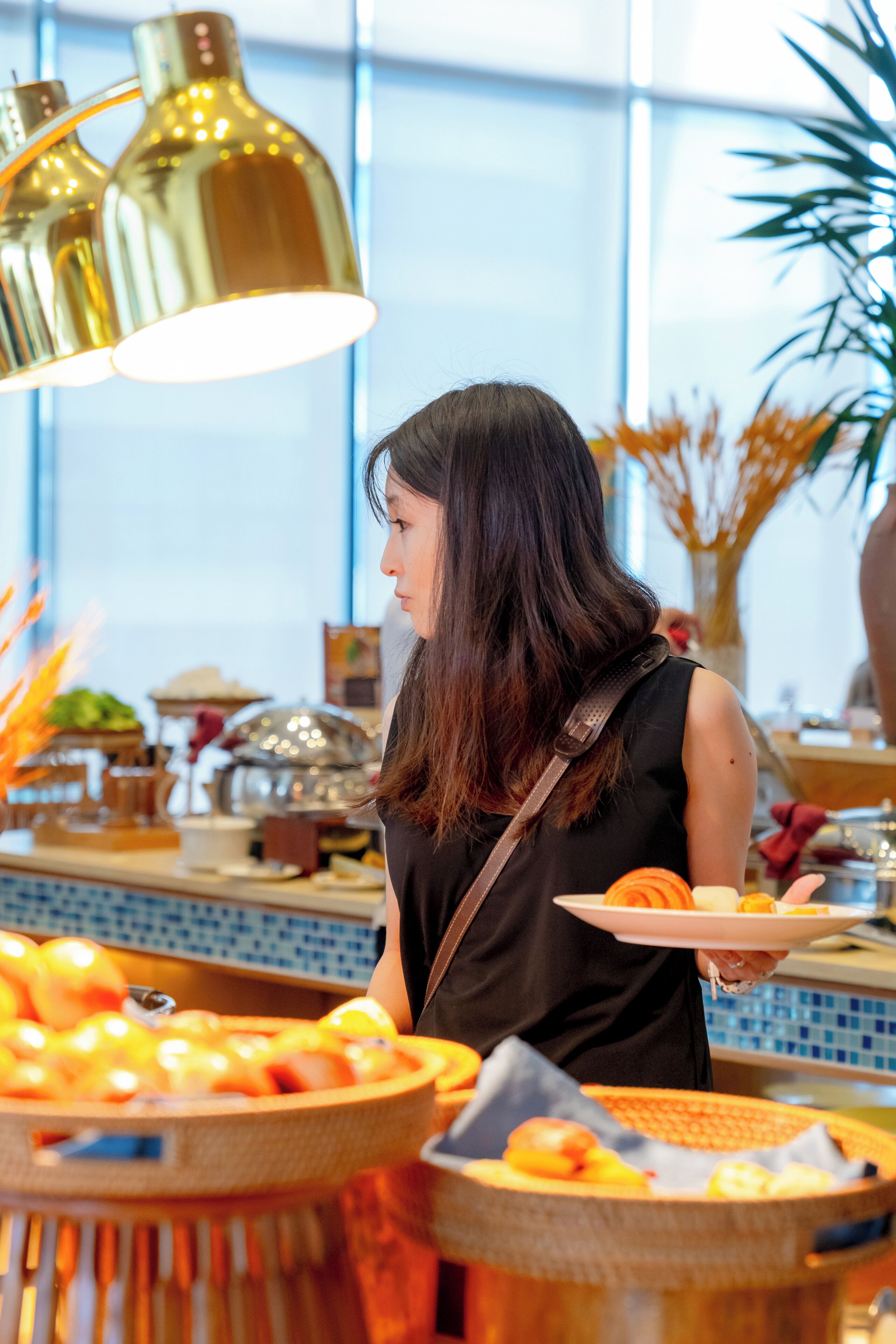 A buffet setup with various food items and a person serving.