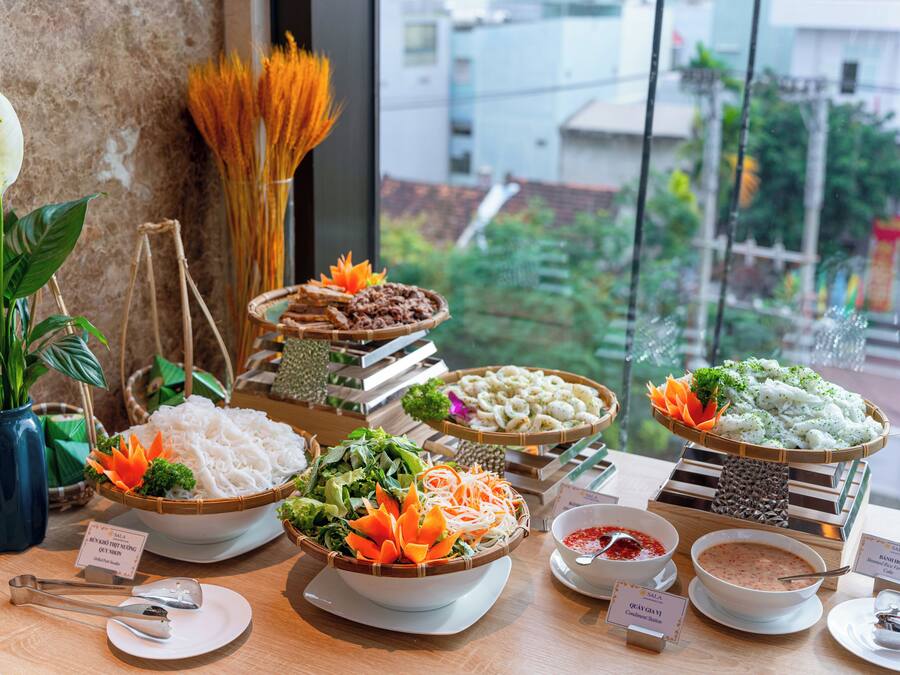 A buffet table with various dishes, including noodles, vegetables, and rice.
