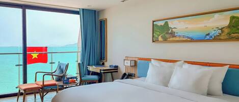 A hotel room with a bed, a desk, a chair, a phone, and a large window with a flag.
