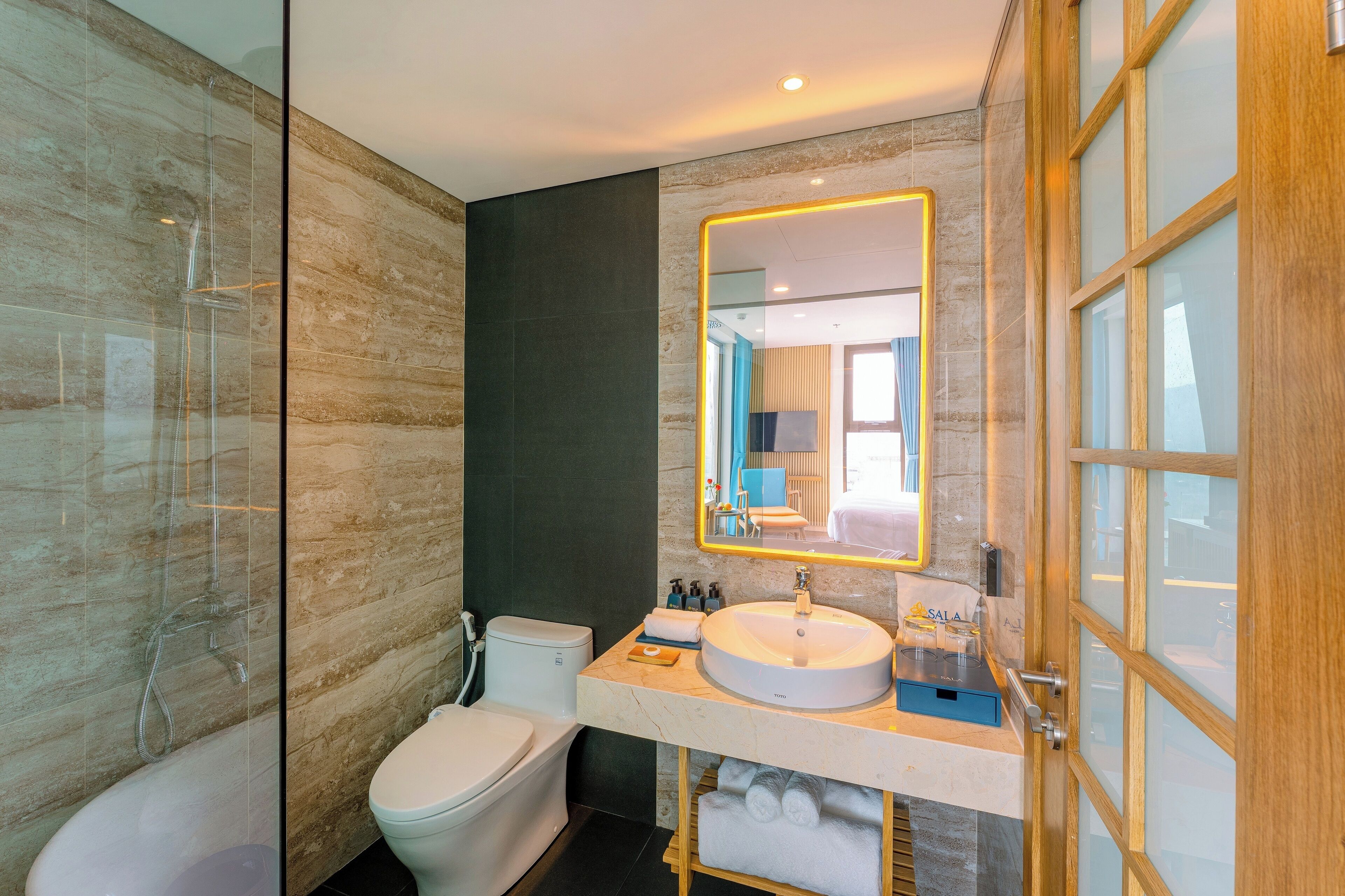 A modern bathroom with a glass shower enclosure, a white toilet, a sink with a mirror, and a towel rack.
