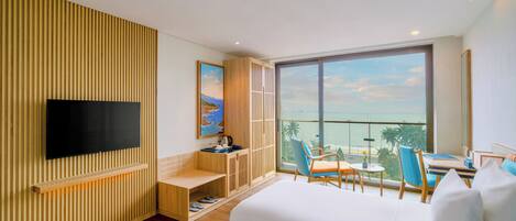 A modern hotel room with a large window, a flat-screen TV, a wooden slatted wall, a desk with a chair, and a bed.