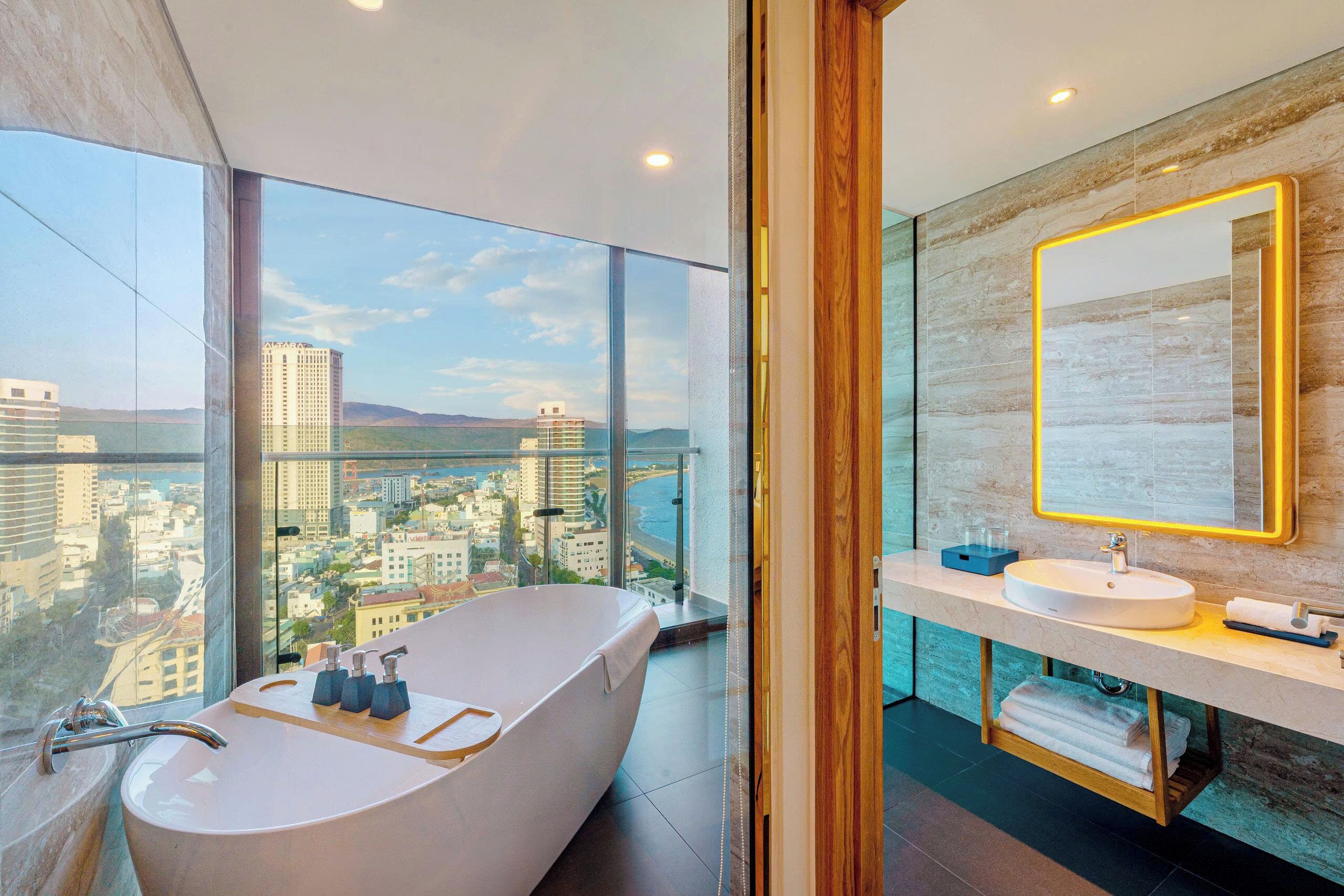 A modern bathroom with a freestanding bathtub, a large mirror, and a view of the cityscape.
