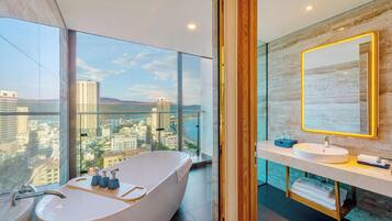 Un baño moderno con una bañera independiente, un espejo grande y vistas a la ciudad.