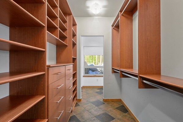 A narrow hallway with wooden shelving units and a window at the end.