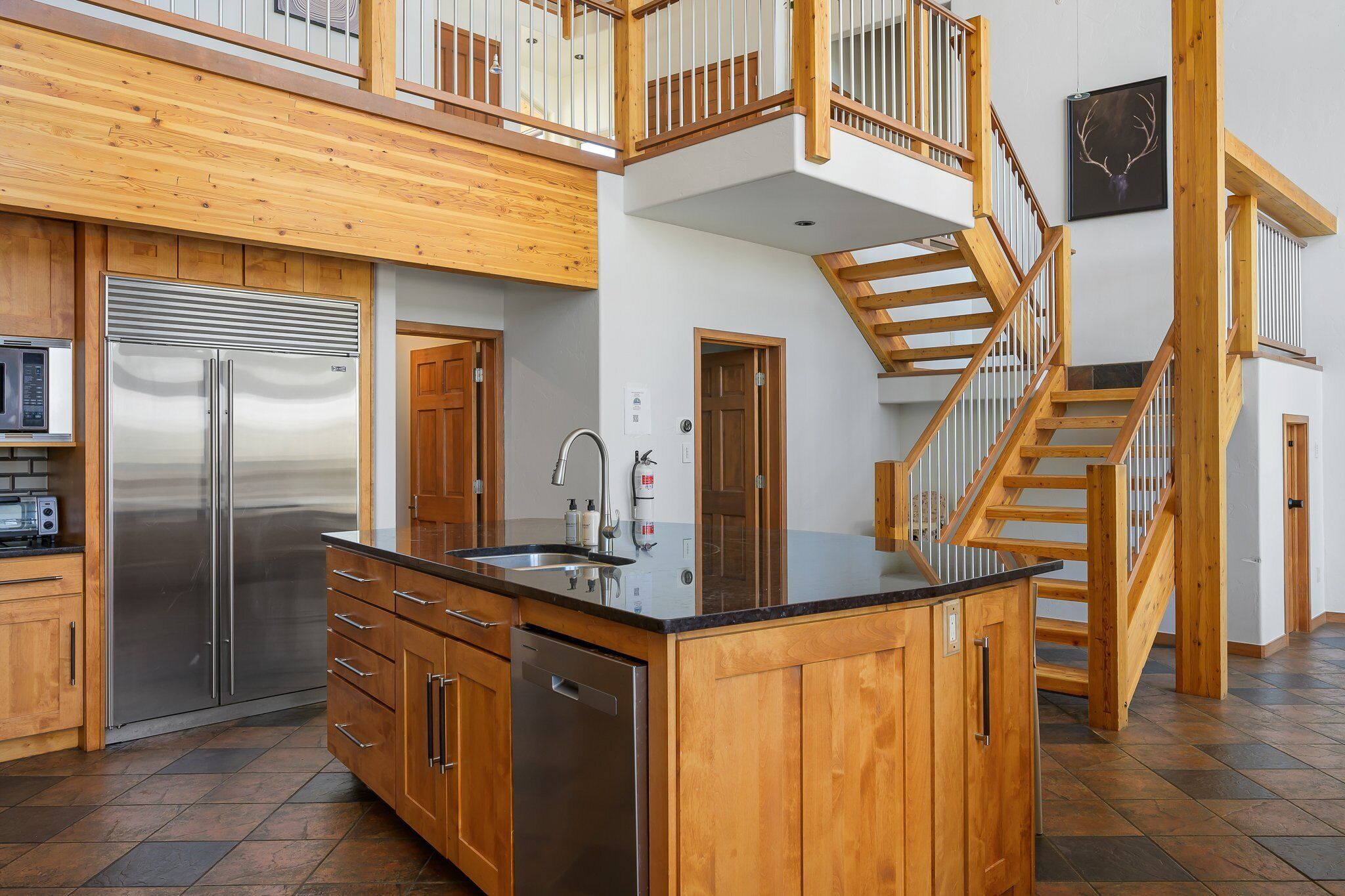 Una cocina moderna con refrigerador de acero inoxidable, gabinetes de madera y una isla grande con pileta.