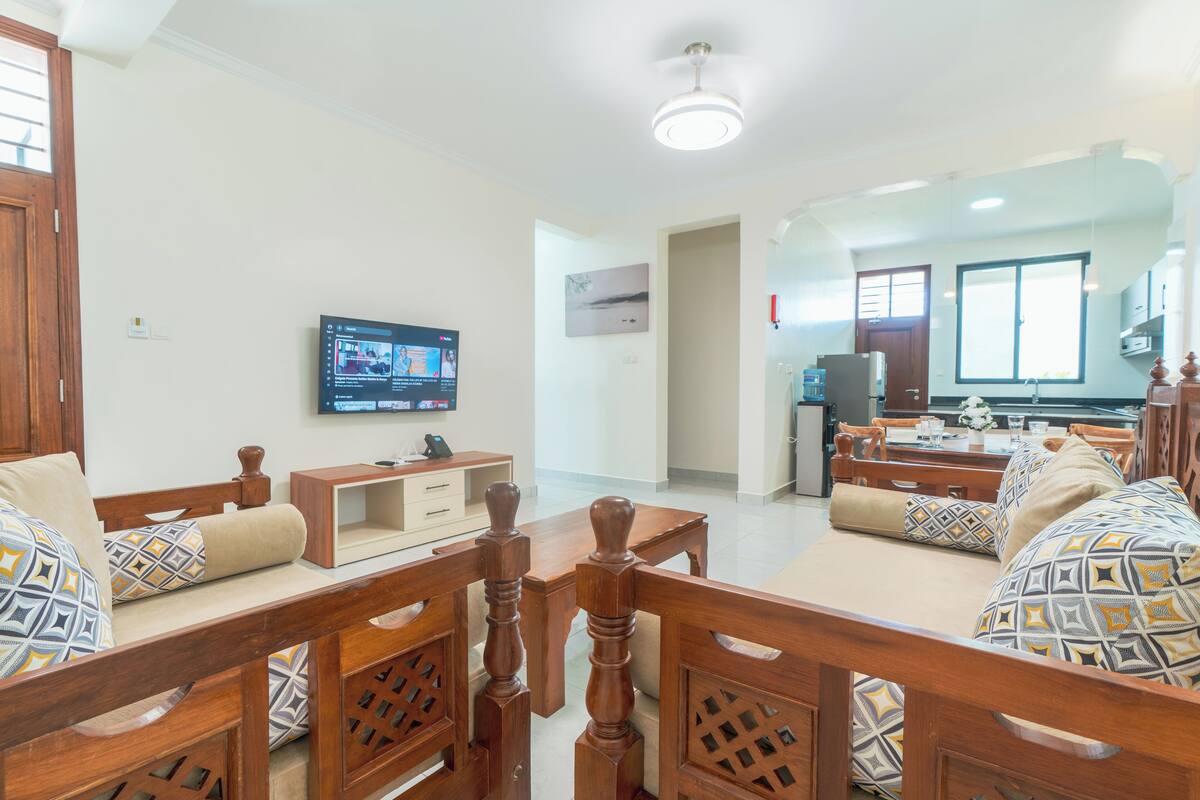 Una sala de estar con televisor, muebles de madera y comedor.