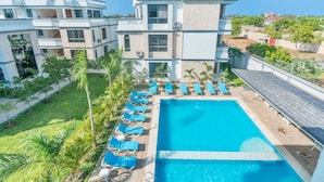 A modern hotel with a swimming pool, multiple balconies, and a well-maintained garden. - Leshan Luxury Villas  (Diani Beach)