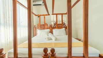 A room with a four-poster bed, white bedding, and a wooden headboard.