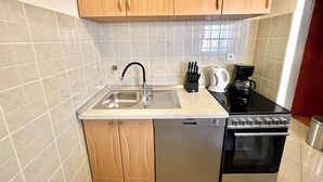 A modern kitchen with a stainless steel sink, a coffee maker, and a built-in oven. - Apartman Mare 3 (Dramalj)