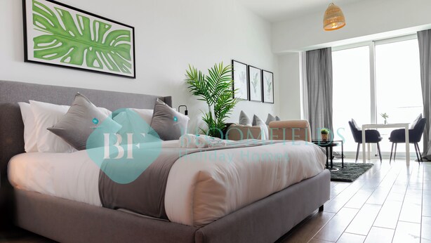 Ein modernes Schlafzimmer mit einem großen Bett, einer Zimmerpflanze und einem Essbereich mit Stühlen und einem Tisch.