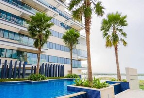A modern hotel with a swimming pool, palm trees, and a view of the ocean. - Bloomfields Studio in Mayan - Yas Island (Abu Dhabi)