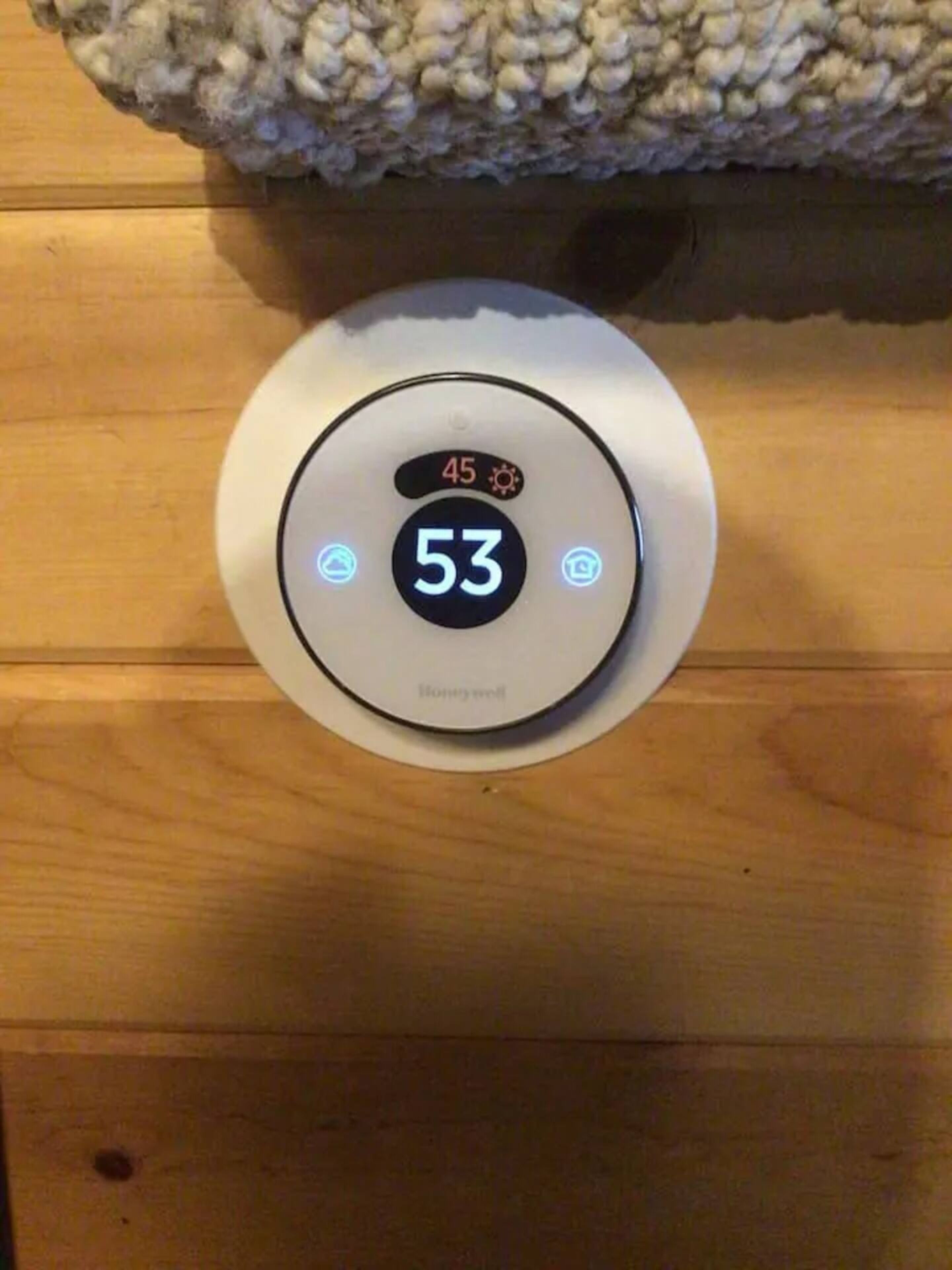 A thermostat with a digital display indicating a temperature of 53 degrees.