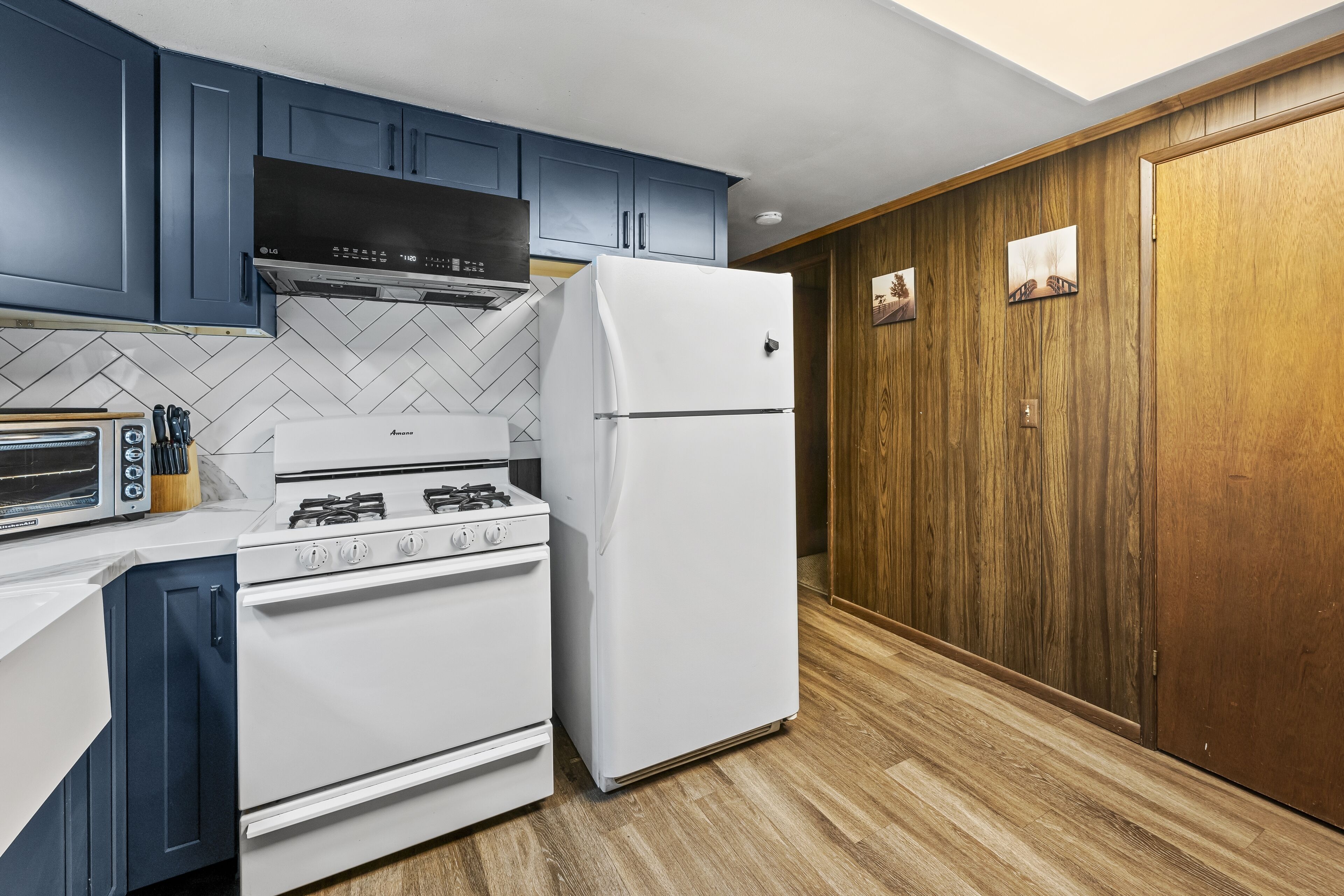 A kitchen with blue cabinets, a white stove, and a white refrigerator.