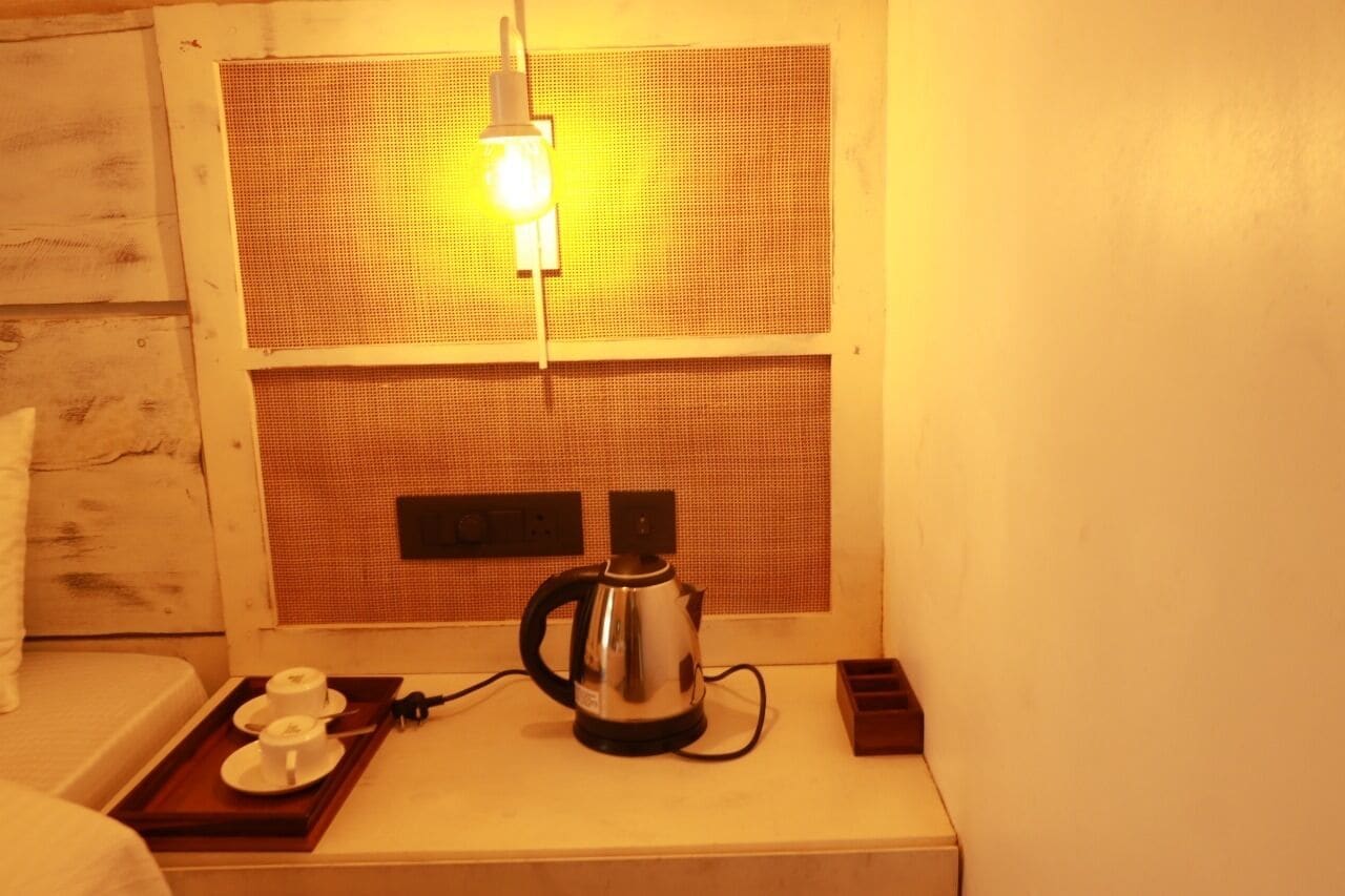 A small kitchenette with a kettle, a tray with cups, and a power outlet.