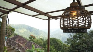 Una escalera rústica conduce a un espacio cubierto con vistas a montañas verdes y exuberantes.