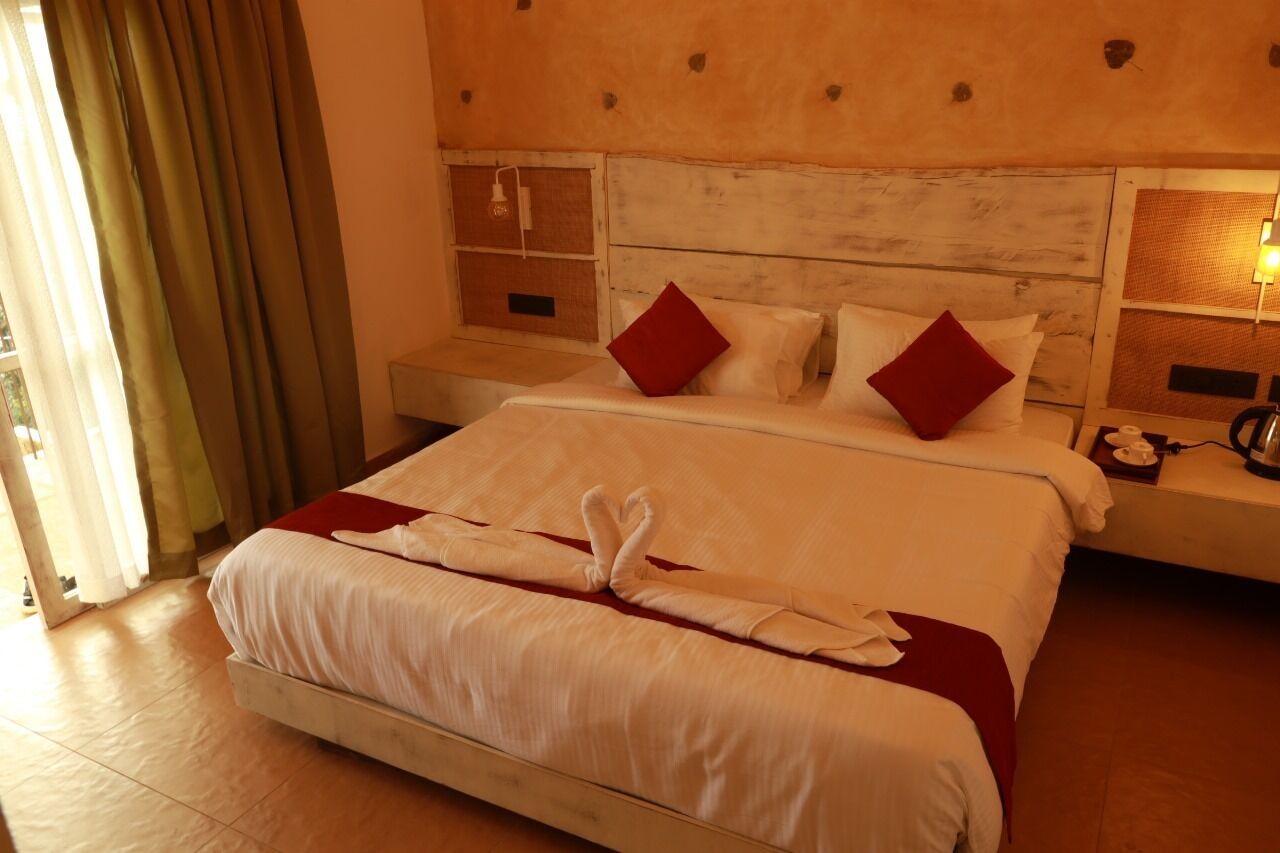 A hotel room with a large bed, two nightstands, a lamp, and a window with curtains.