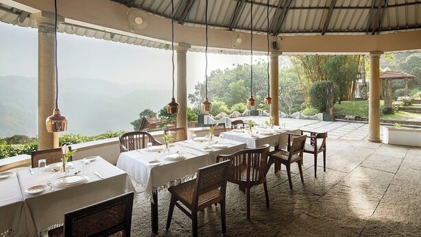 Un restaurante con mesas dispuestas para comer, ventanas amplias y vistas a las montañas.