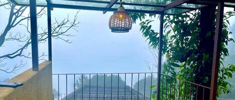 Área externa coberta com uma escada de madeira que leva a um guarda-corpo de metal com vista para uma rua.