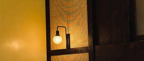 Een hotelkamer met een bed, een wandlamp en een grote spiegel.