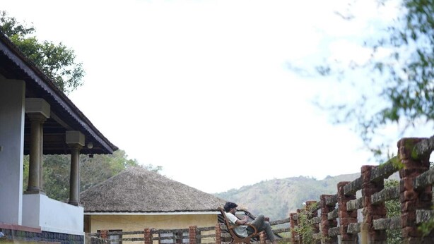 A rustic building with a thatched roof and a brick wall.