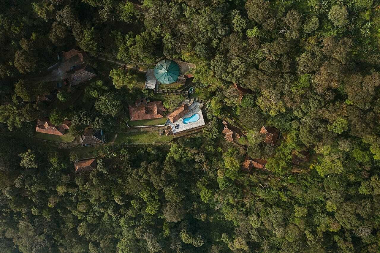 An aerial view of a secluded resort with multiple buildings, a swimming pool, and lush greenery.