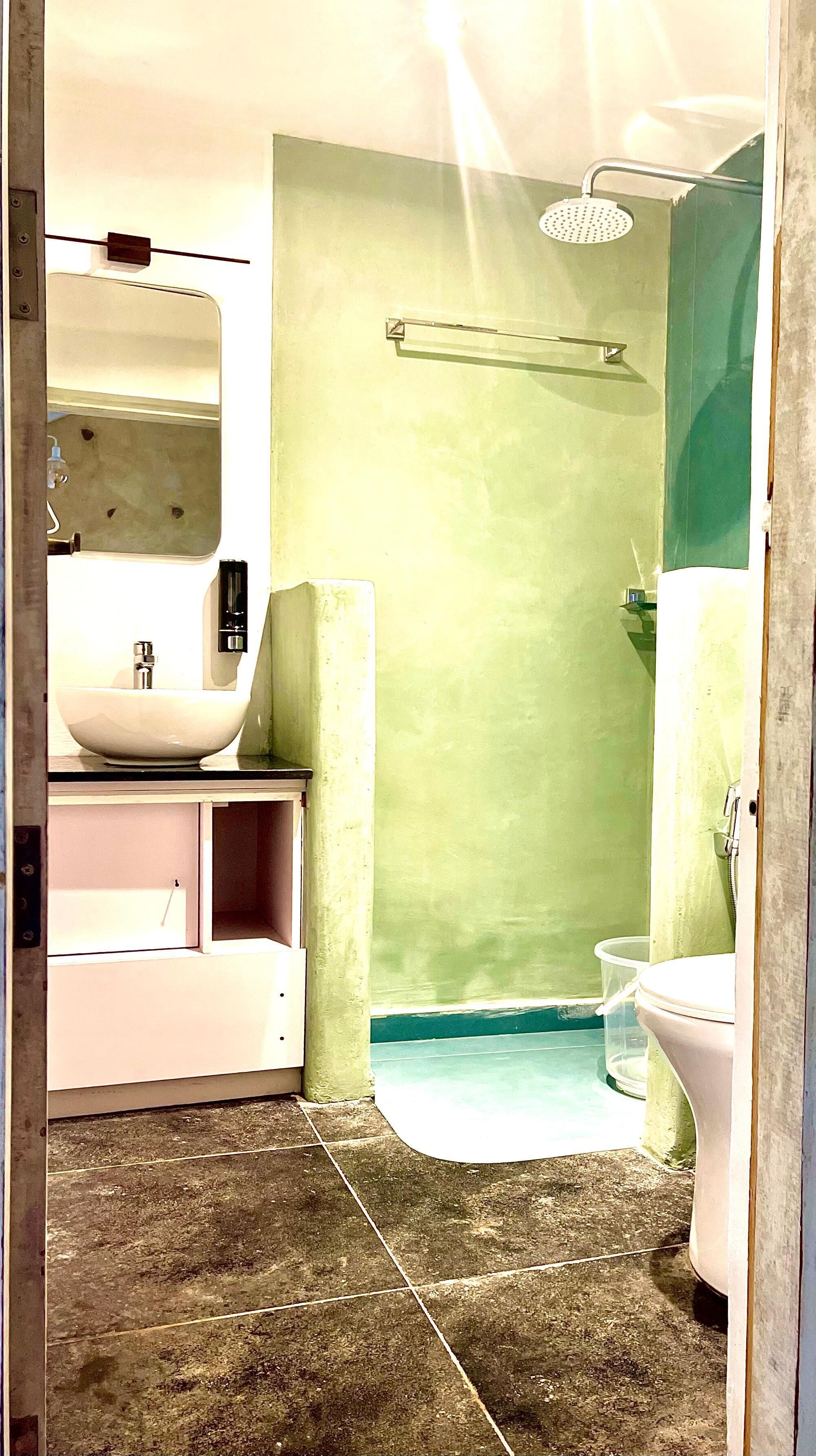 A bathroom with a white sink, a mirror, a shower with a glass door, and a toilet.