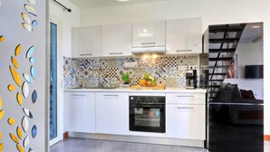 Eine moderne Küche mit weißen Schränken, einer gemusterten Spritzschutzleiste, einem eingebauten Backofen und einem schwarzen Kühlschrank.