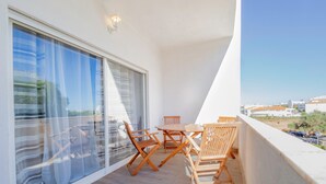 Ein Balkon mit Tisch und Stühlen, großen Fenstern und Blick auf Gebäude.
