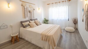 Ein Schlafzimmer mit Bett, Deckenventilator, Nachttisch und Wandleuchte.