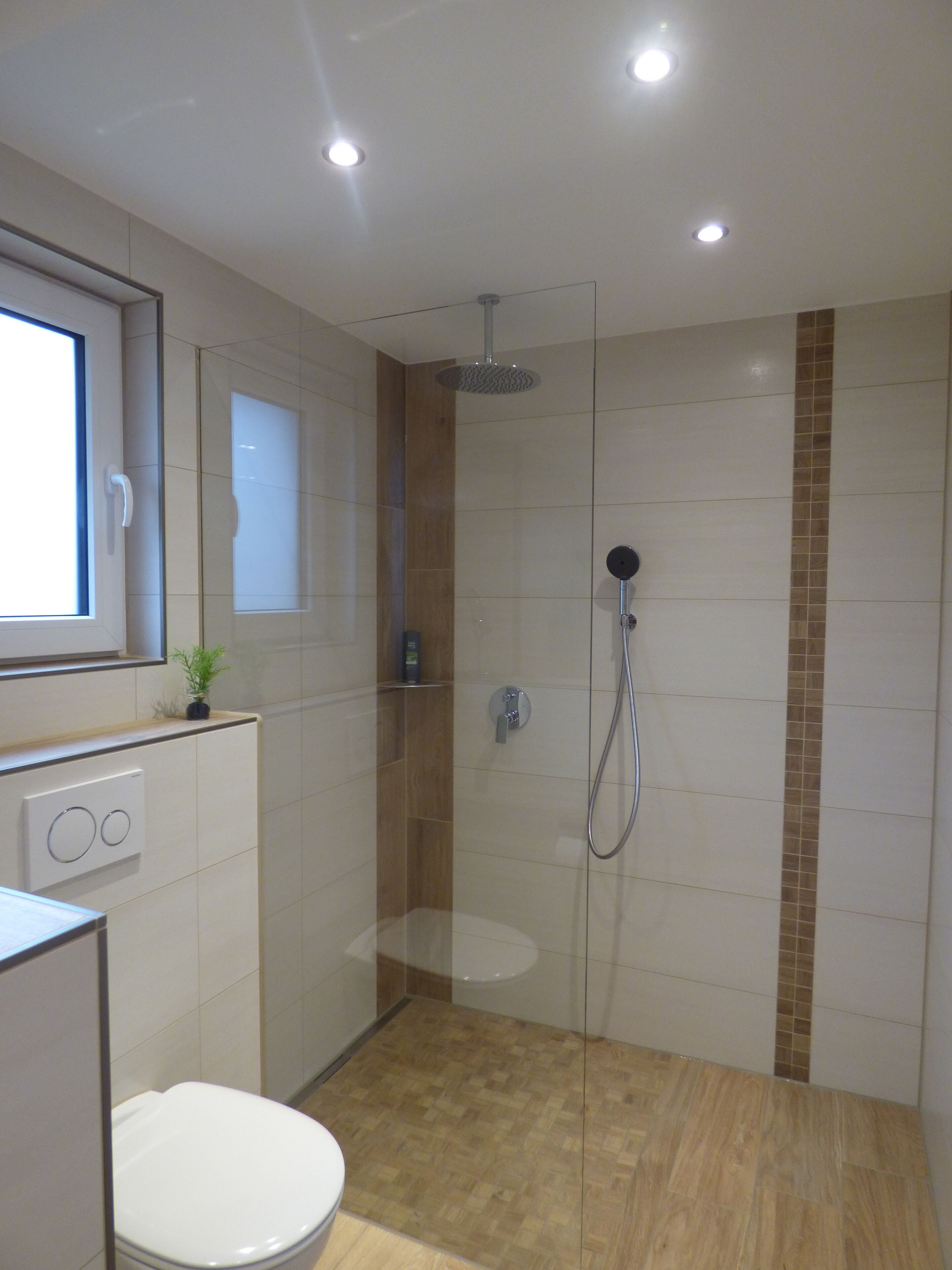 Un bany modern amb dutxa de vidre, vàter i un lavabo amb mirall a la part superior.
