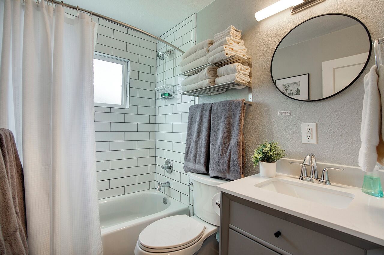 A bathroom with a bathtub, toilet, sink, and a mirror.