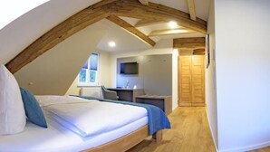 A bedroom with a loft-style ceiling, a bed, a desk, a chair, and a wardrobe. - Gasthaus Adler (Konstanz)