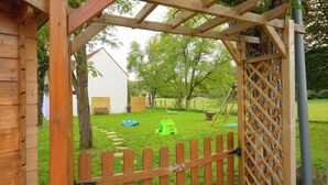 A wooden gate leading to a grassy yard with a swing set and a small shed. - "Les Genêts" your charming gîte in Essonne (Buno-Bonnevaux)
