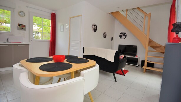 A modern living room with a dining area, a staircase, and a kitchen. - "Les Genêts" your charming gîte in Essonne (Buno-Bonnevaux)
