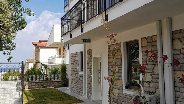 A two-story building with a balcony, stone facade, and a small garden area. - Datça Zeytinevleri Apart (Datça)